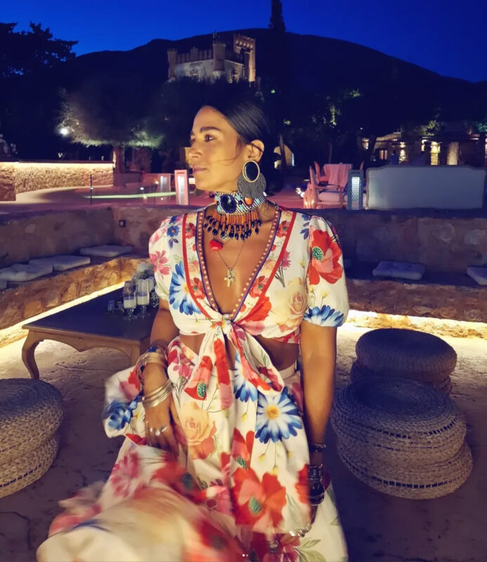 Ελένα καλεσμένη σε καλοκαιρινό γάμο σε κτήμα, με floral φόρεμα και πλούσιο statement τσόκερ, wedding guest jewelry guide look.