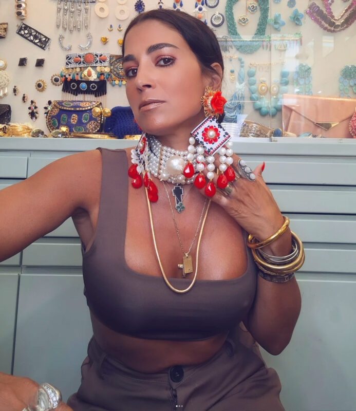 Double Trouble Woman με statement σκουλαρίκια και τσόκερ μπροστά σε βιτρίνα κοσμημάτων – αποθήκευση κοσμημάτων χωρίς να μπλέκονται.