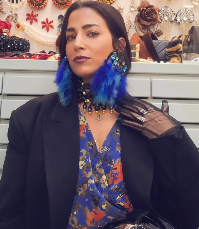 Γυναίκα με μπλε φτερωτά statement σκουλαρίκια και μαύρο τσόκερ στο κατάστημα Double Trouble, οδηγός για σκουλαρίκια για σχήμα προσώπου.