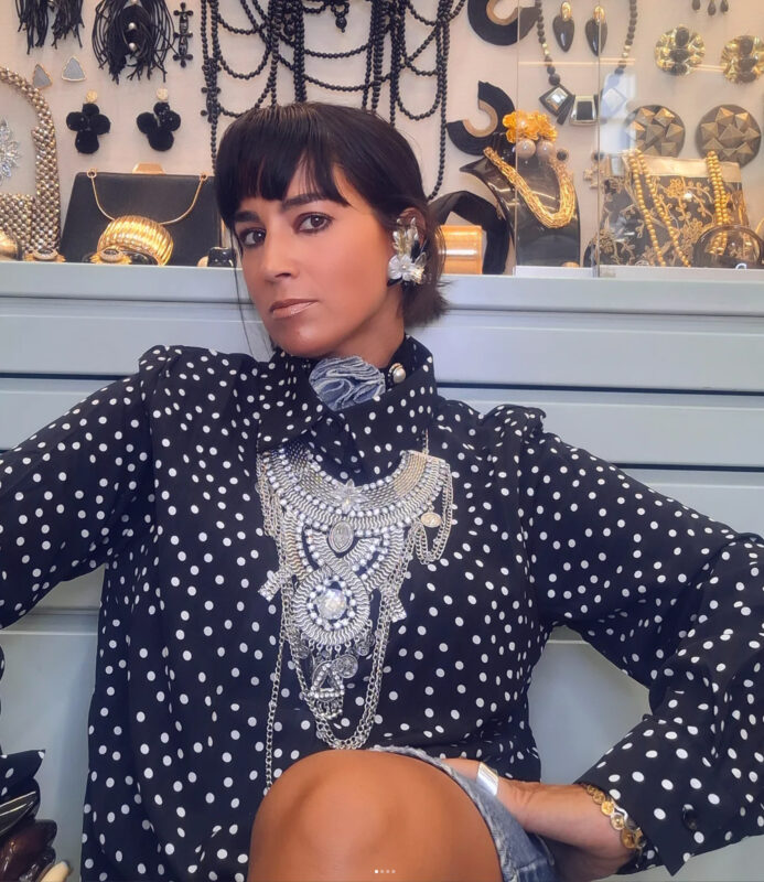 Double Trouble Girl με πουά πουκάμισο και ασημένιο statement κολιέ μέσα στο στούντιο κοσμημάτων της.