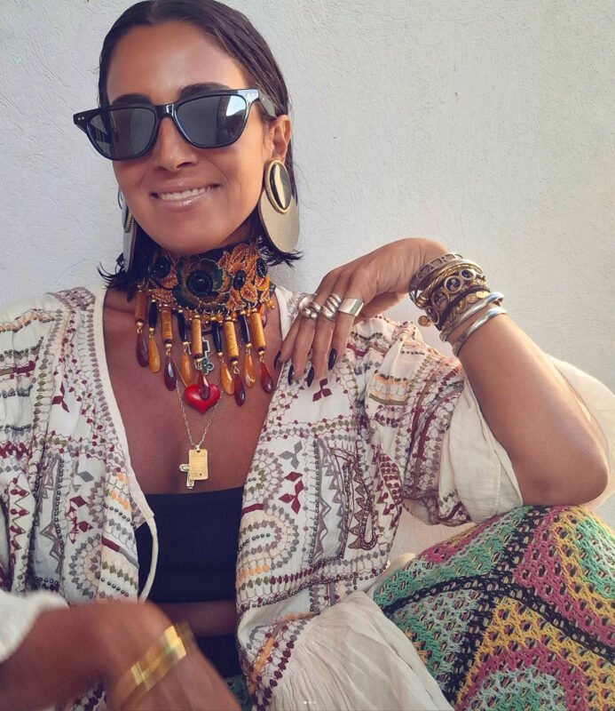 Γυναίκα με boho summer look, dramatic τσόκερ, μάξι σκουλαρίκια, βραχιόλια και δαχτυλίδια σε maximal styling