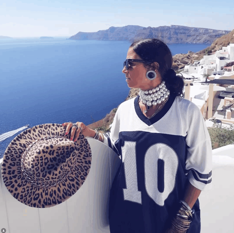 Έλενα με oversized t-shirt στη Σαντορίνη, πέρλες στον λαιμό, statement σκουλαρίκια, animal καπέλο και πολλά βραχιόλια.
