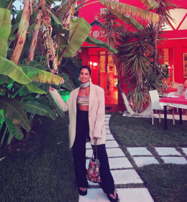Γυναίκα με blazer, crop top, statement τσόκερ, layered κολιέ και μεταλλικά βραχιόλια σε βραδινό look.