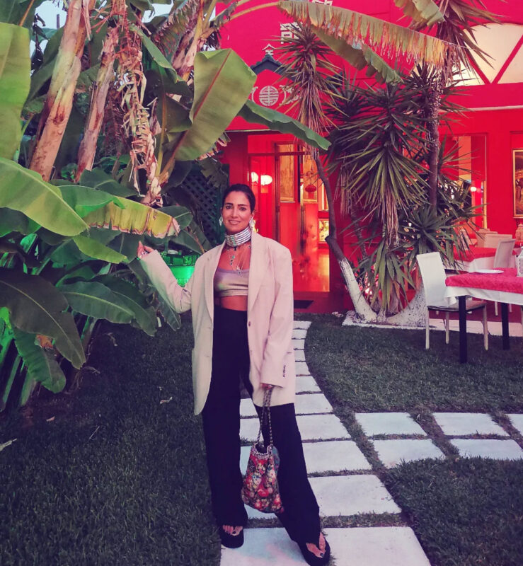 Γυναίκα με blazer, crop top, statement τσόκερ, layered κολιέ και μεταλλικά βραχιόλια σε βραδινό look.