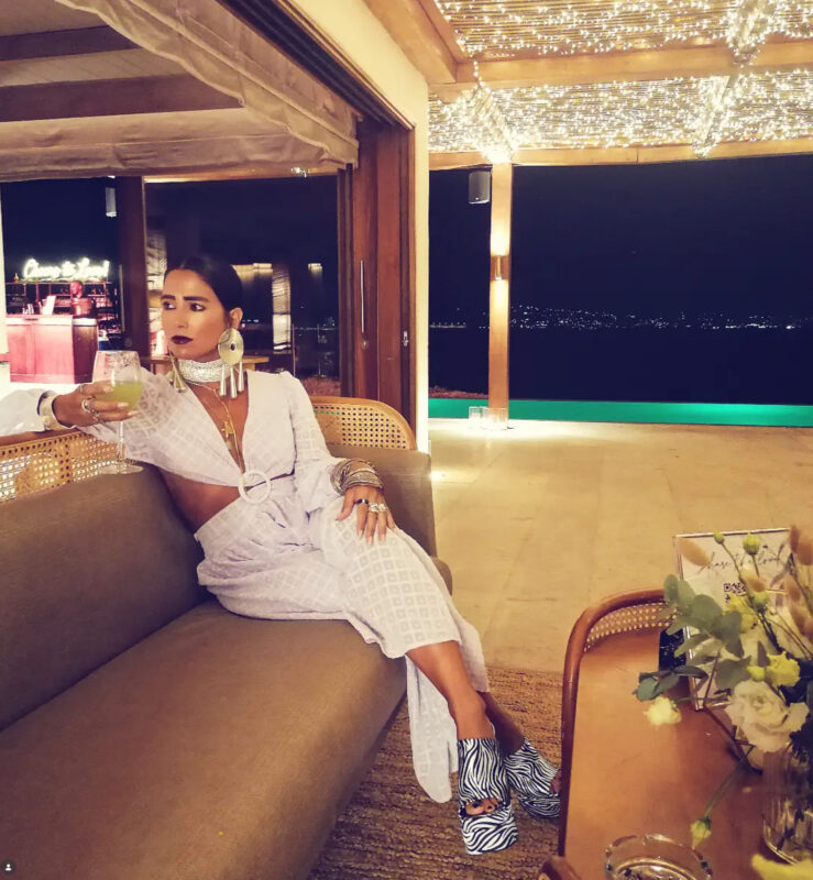 Γυναίκα σε private event στο Island Athens Riviera Resort με λευκό cut-out βραδινό σύνολο, μεγάλο ασημί τσόκερ, statement σκουλαρίκια, πολλά βραχιόλια και zebra platform παπούτσια.