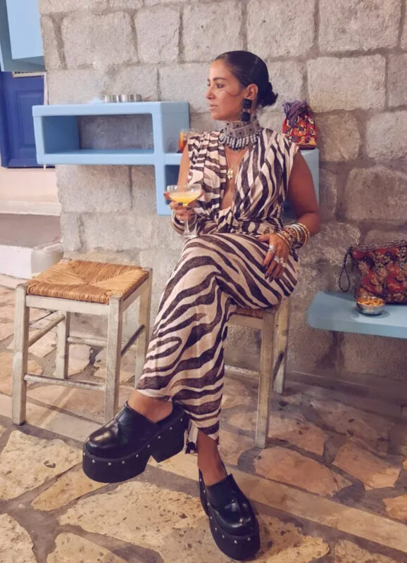 Γυναίκα με zebra print καλοκαιρινό outfit, μεγάλο μεταλλικό statement choker, μαύρα σκουλαρίκια, πολλά βραχιόλια και μαύρα platform παπούτσια.